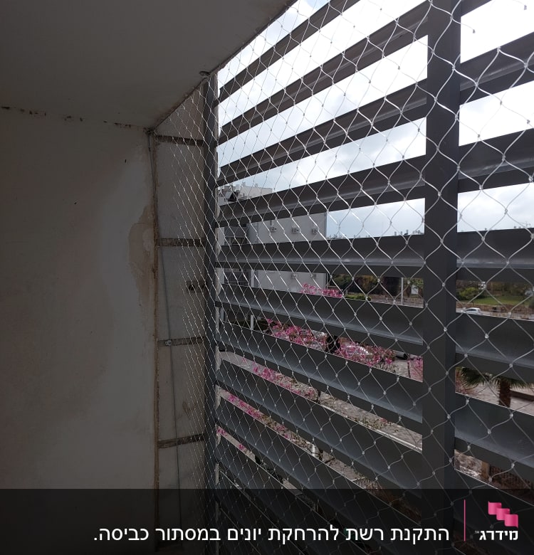 רשת מתכת מותקנת על חלון למניעת כניסת יונים